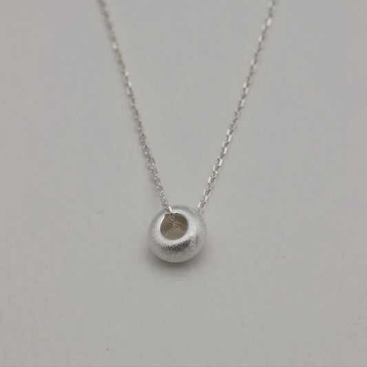 Close-up of the Noémie Necklace featuring a frosted silver bead on a delicate 925 sterling silver chain.