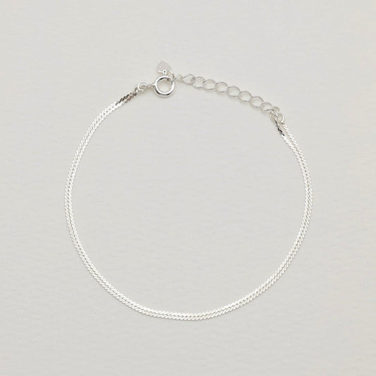 Sterling silver dual-strand bracelet with polished finish and extension chain on cream background