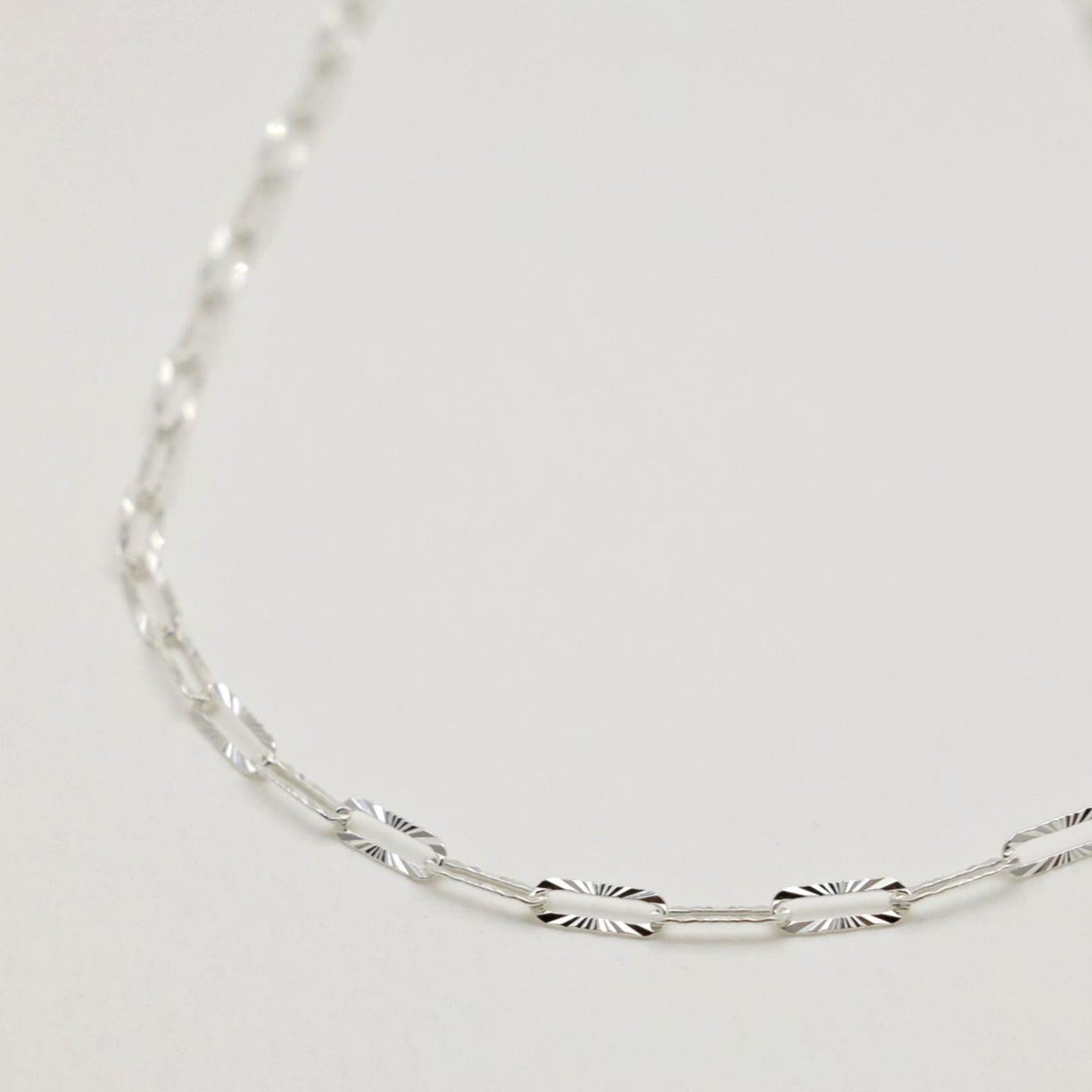 Close-up of the Solène Necklace in sterling silver, showcasing its faceted, reflective links.