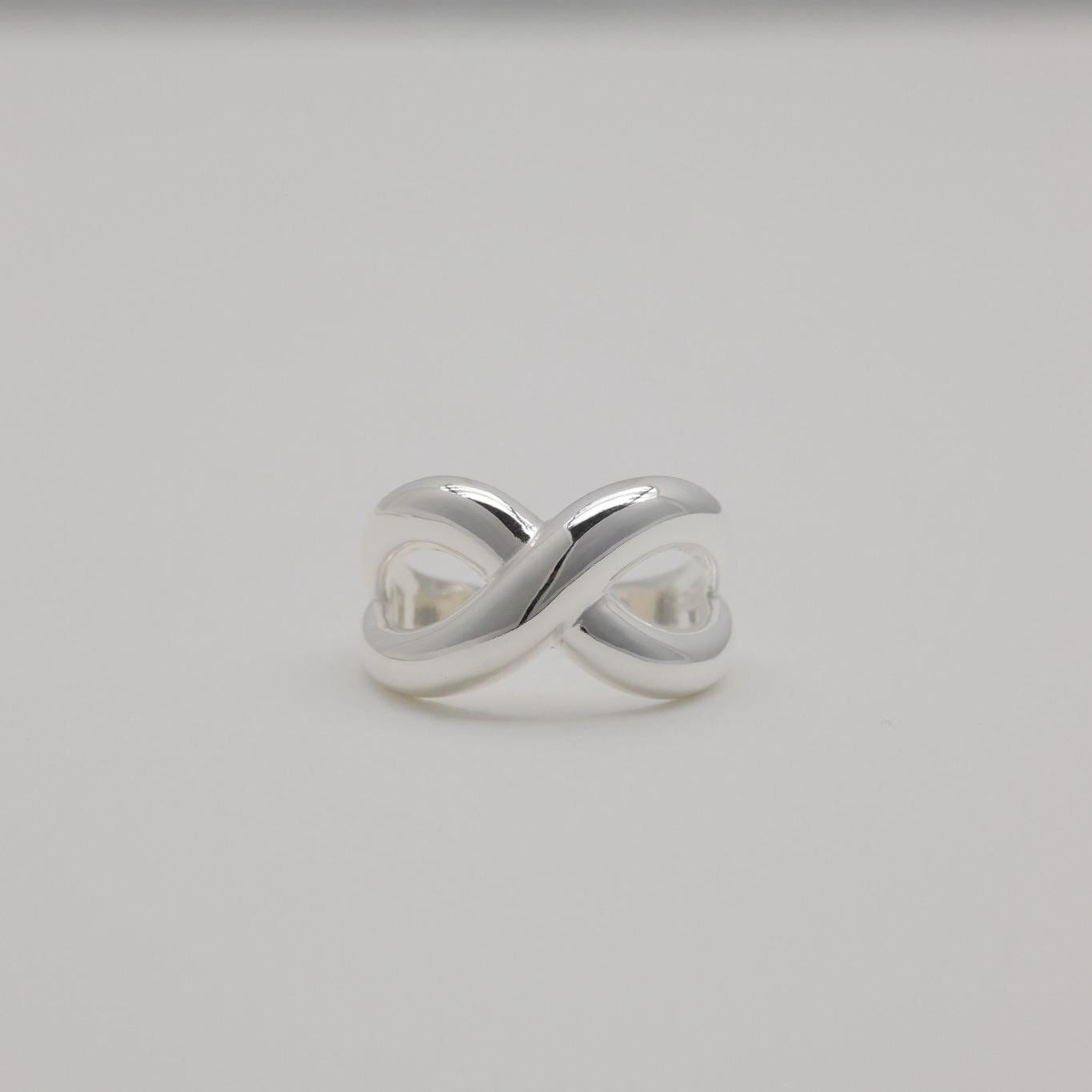 Axelle Crossover Ring in sterling silver with polished curved twist design and open adjustable band.