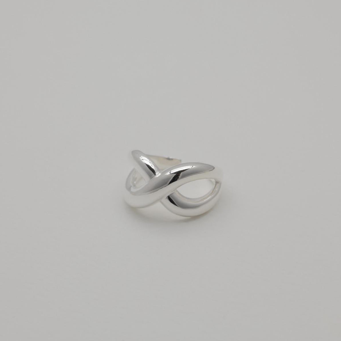 Axelle Crossover Ring in sterling silver with polished curved twist design and open adjustable band.