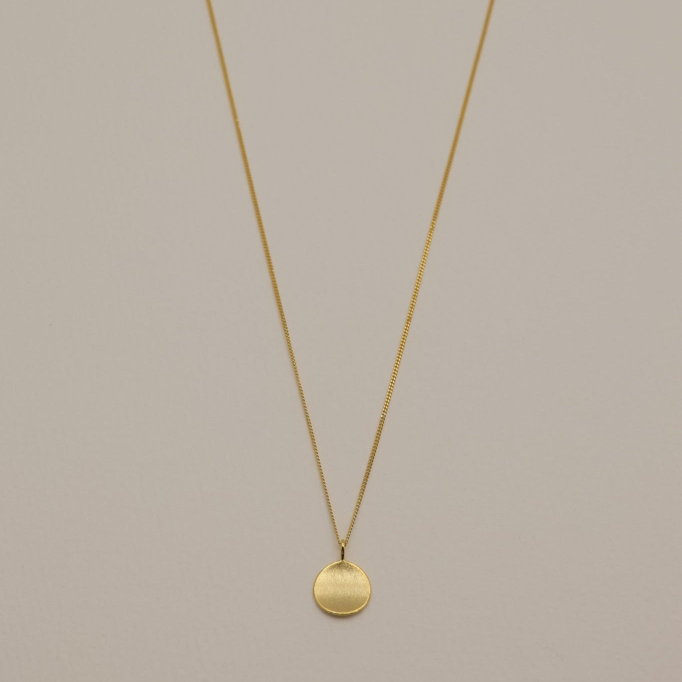  A full-view image of the Amélie Engravable Necklace in gold vermeil, featuring a round, plain pendant on a fine chain.