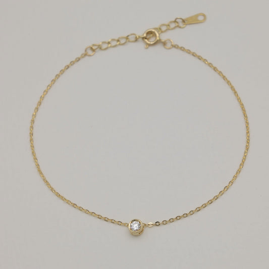 Minimalist gold bracelet with lab-grown diamond bezel set in center

