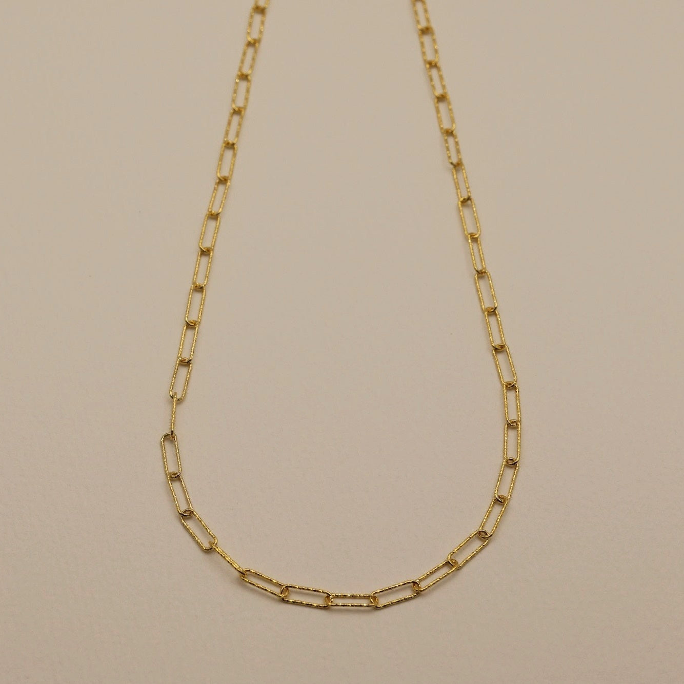 A gold vermeil textured chain necklace laid flat on a neutral background.