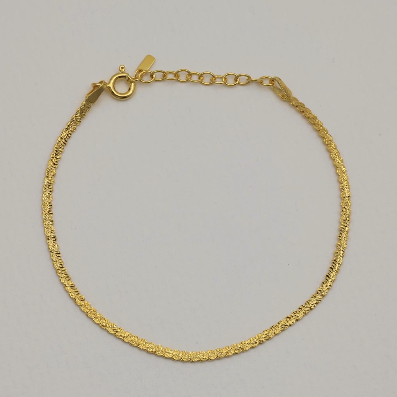 Gold vermeil herringbone bracelet photographed from a slight distance, showing full chain curve and clasp.
