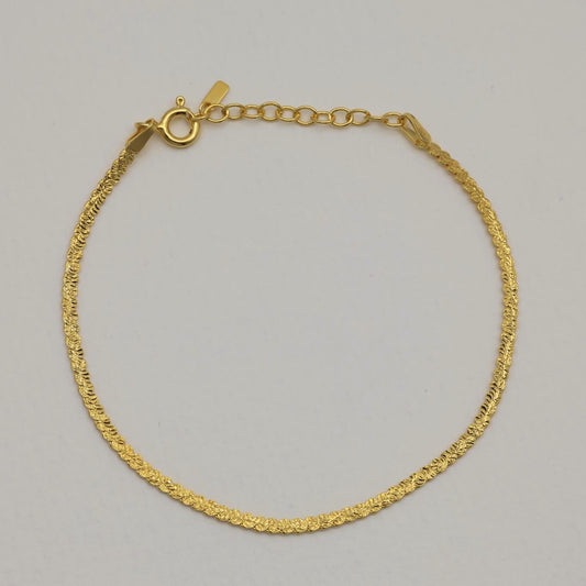 Gold vermeil herringbone bracelet photographed from a slight distance, showing full chain curve and clasp.
