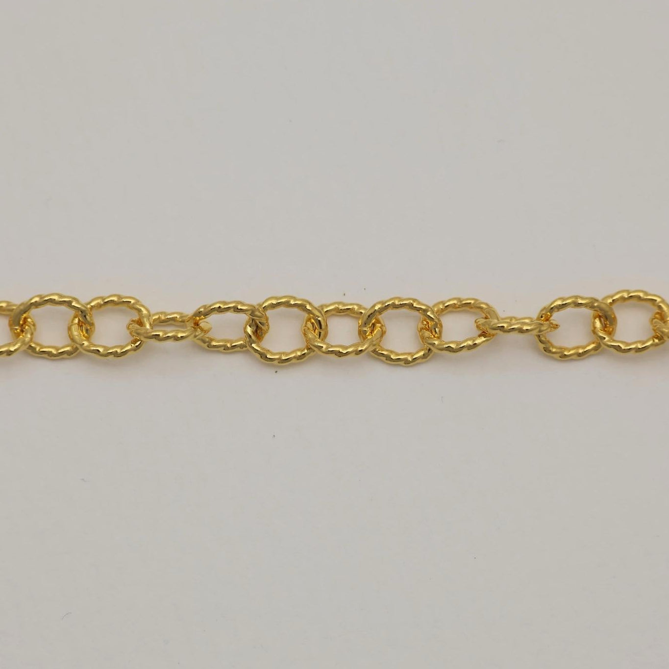 Vertical close-up of a gold vermeil chain bracelet, displaying the repeating pattern of wavy, ripple-textured links.

