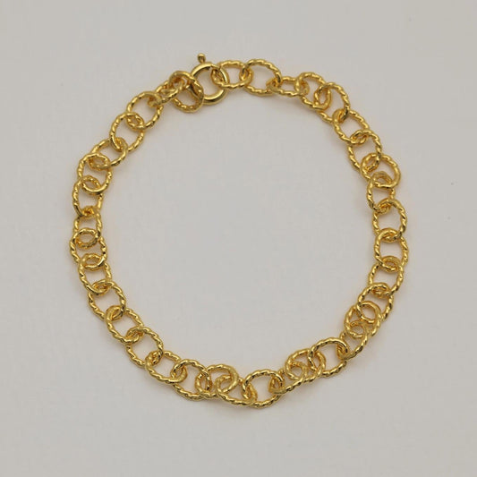 Full view of a gold vermeil bracelet laid flat in a circle, highlighting the textured round links and spring clasp.

