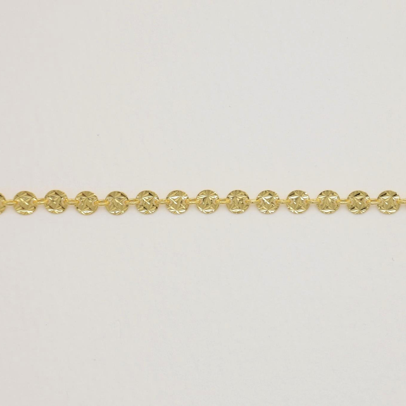Flat lay of the Cassiopée Bracelet in gold vermeil showing star-cut disc design.

