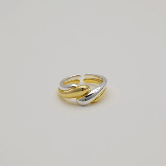 Silver and gold crossover rings displayed flat on a light backdrop

