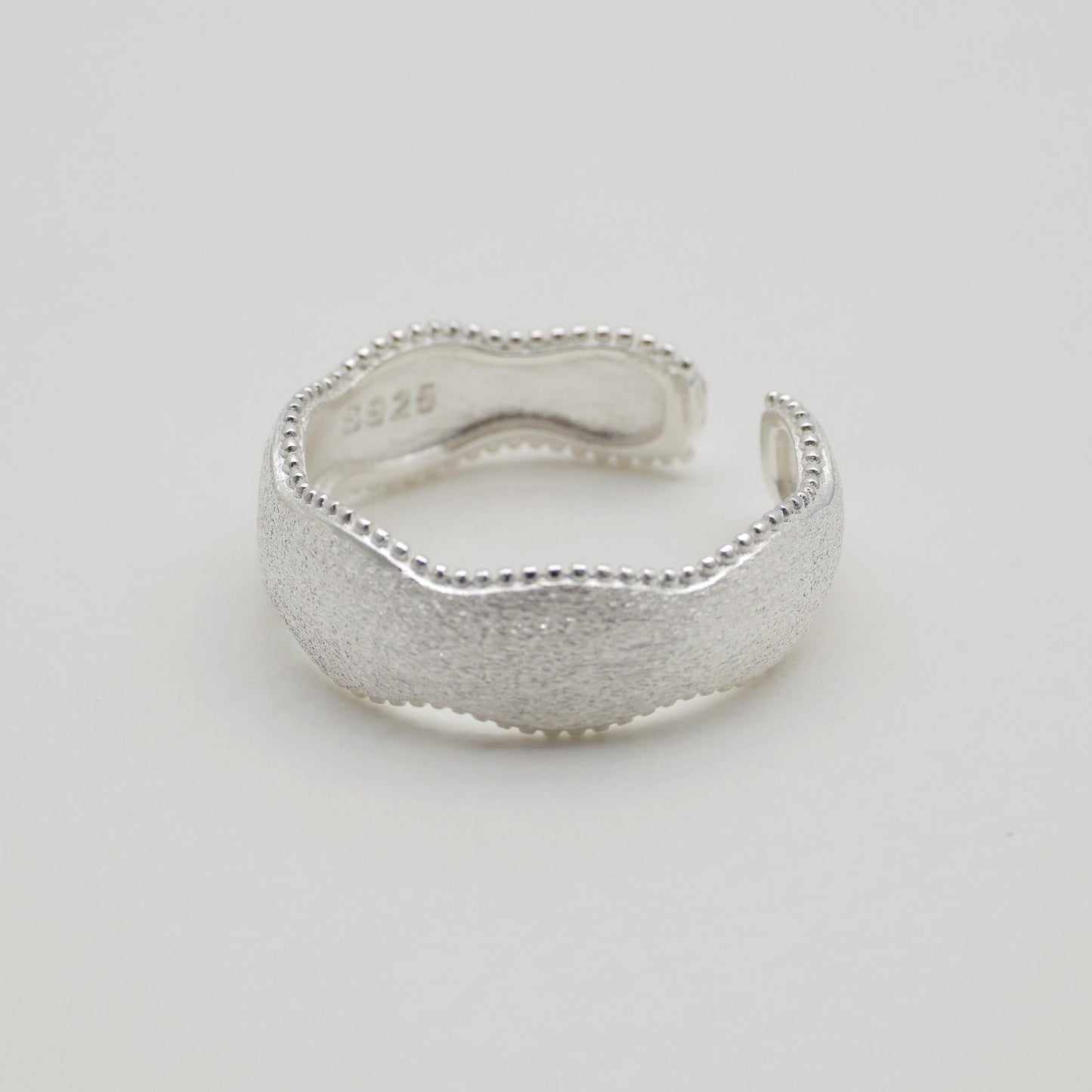 Side angle view of sculptural silver ring, open band design


