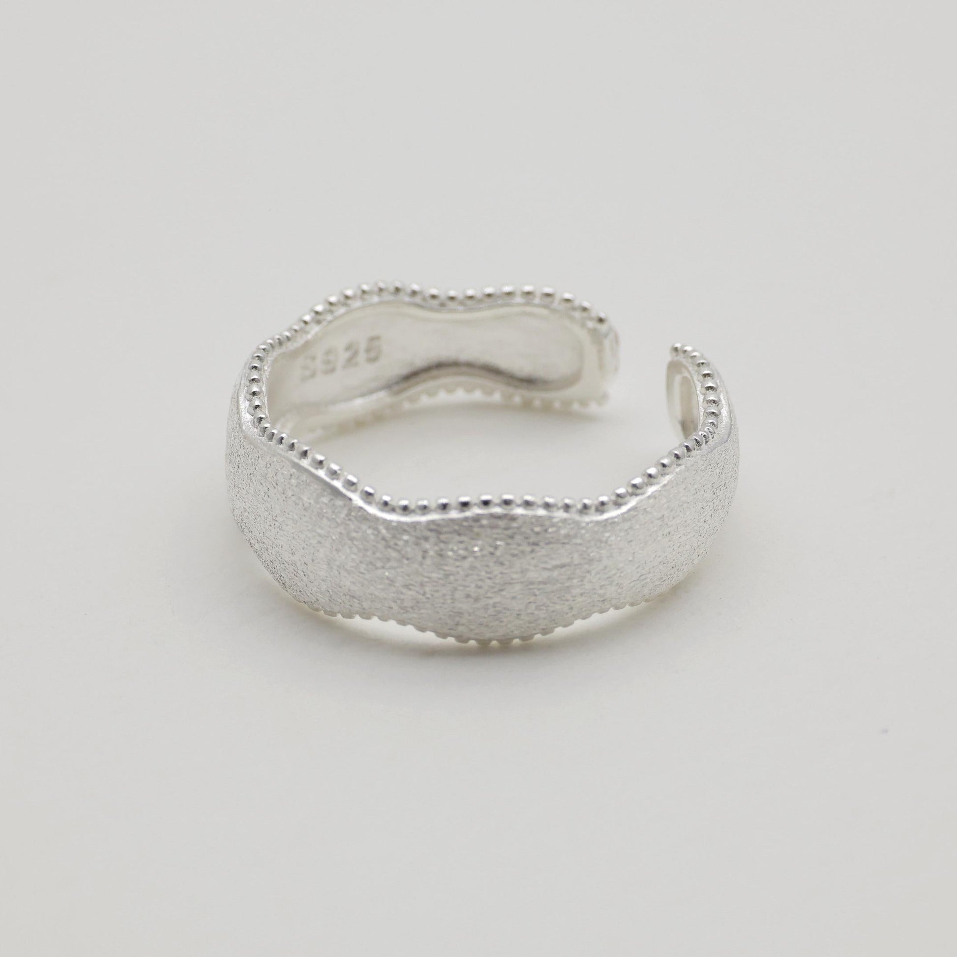 Side angle view of sculptural silver ring, open band design

