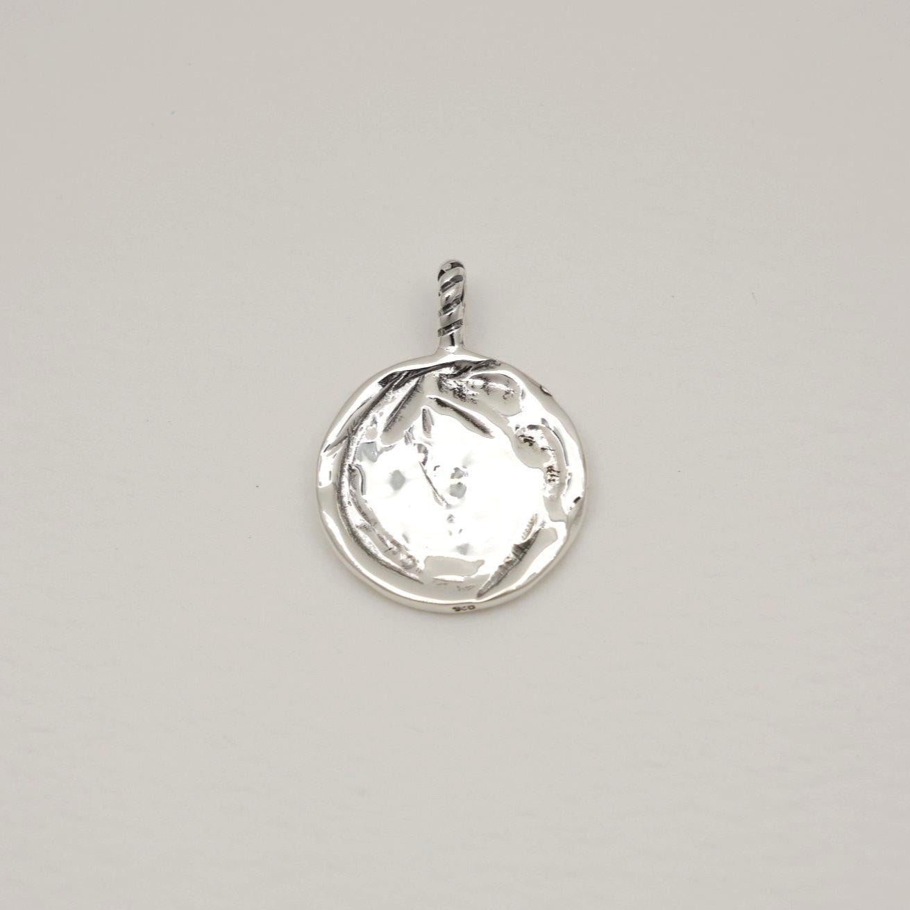 Silver pendant with a clear gemstone on a light gray background