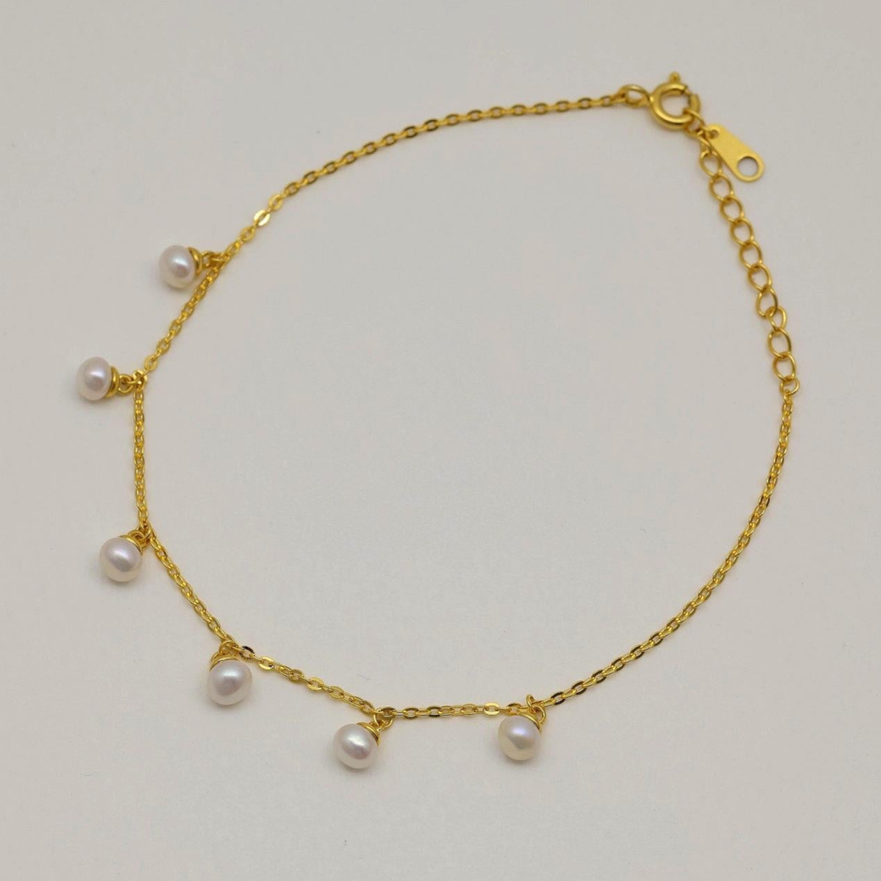 Gold vermeil chain bracelet with six small natural pearl drops, displayed on a neutral background.