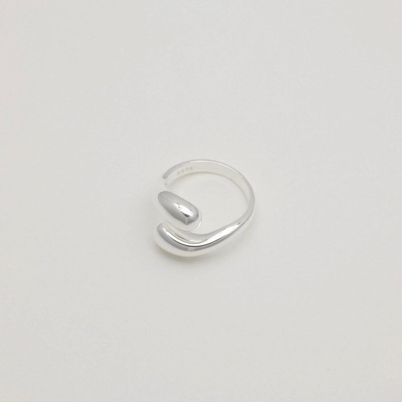 Sculptural sterling silver ring with teardrop-like ends and a polished adjustable wrap design.
