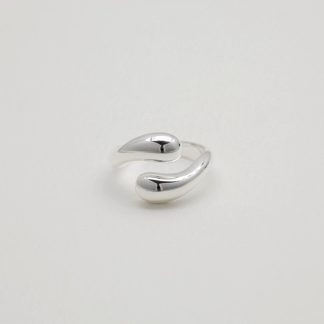 Sculptural sterling silver ring with teardrop-like ends and a polished adjustable wrap design.