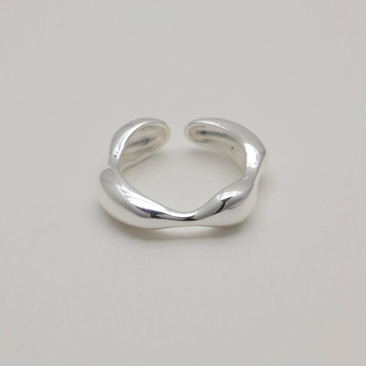 Adjustable sculptural silver ring with fluid curves and polished finish, open-ended band design.