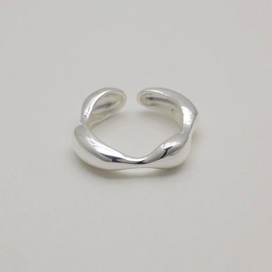 Adjustable sculptural silver ring with fluid curves and polished finish, open-ended band design.