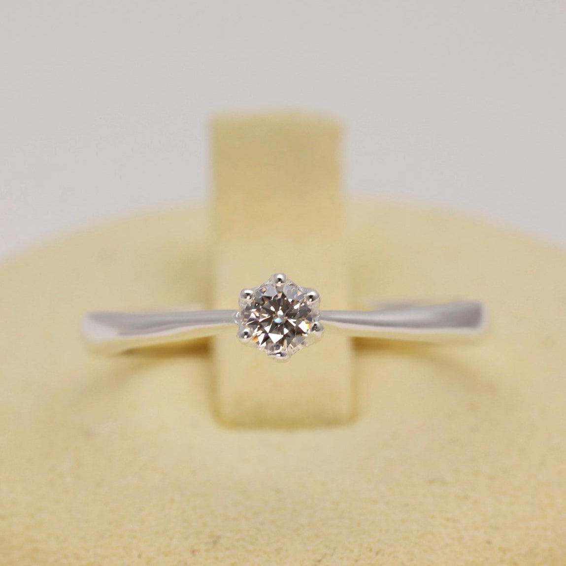 Diamond ring in a yellow jewelry box on a light gray background