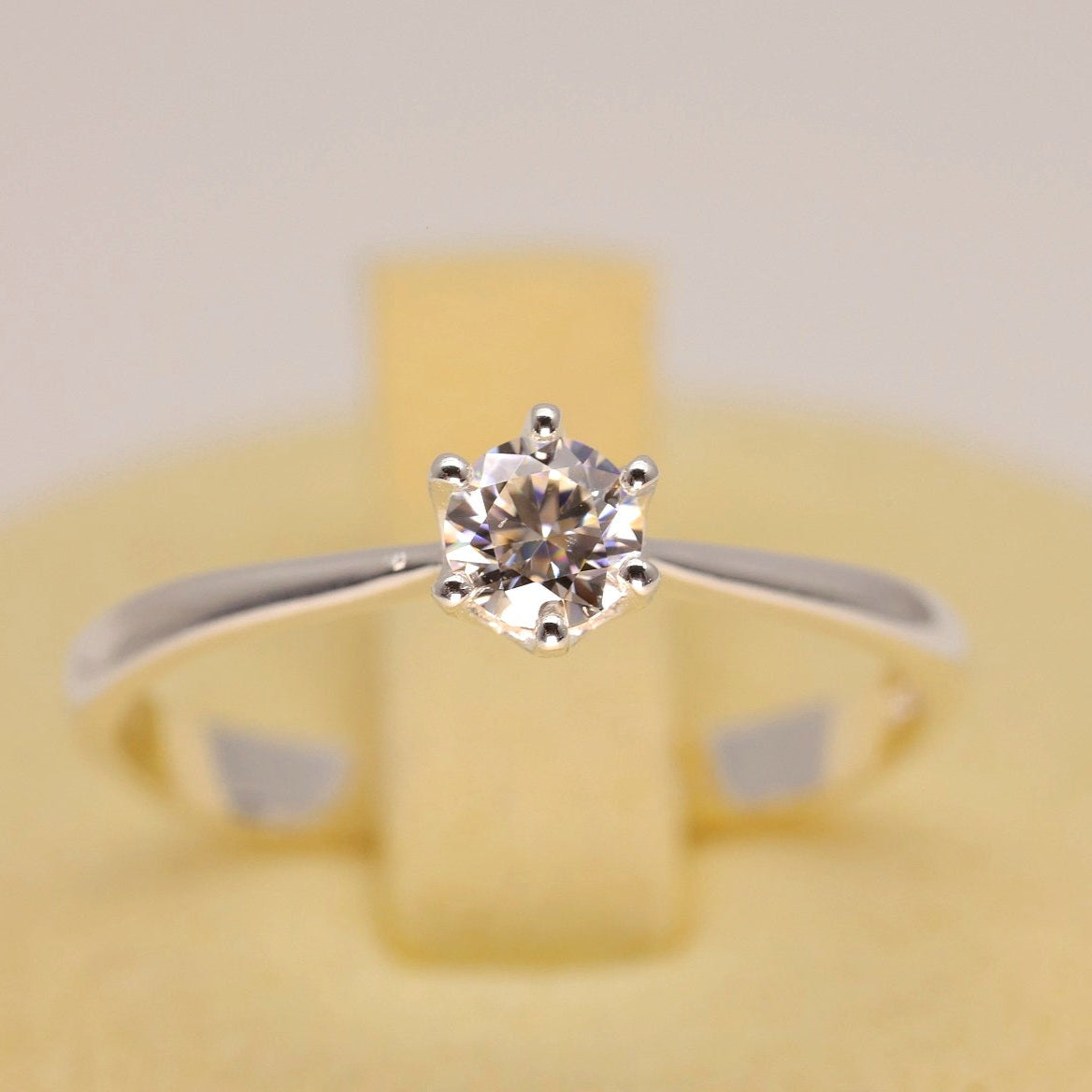 Diamond ring on a yellow cushion with a plain background