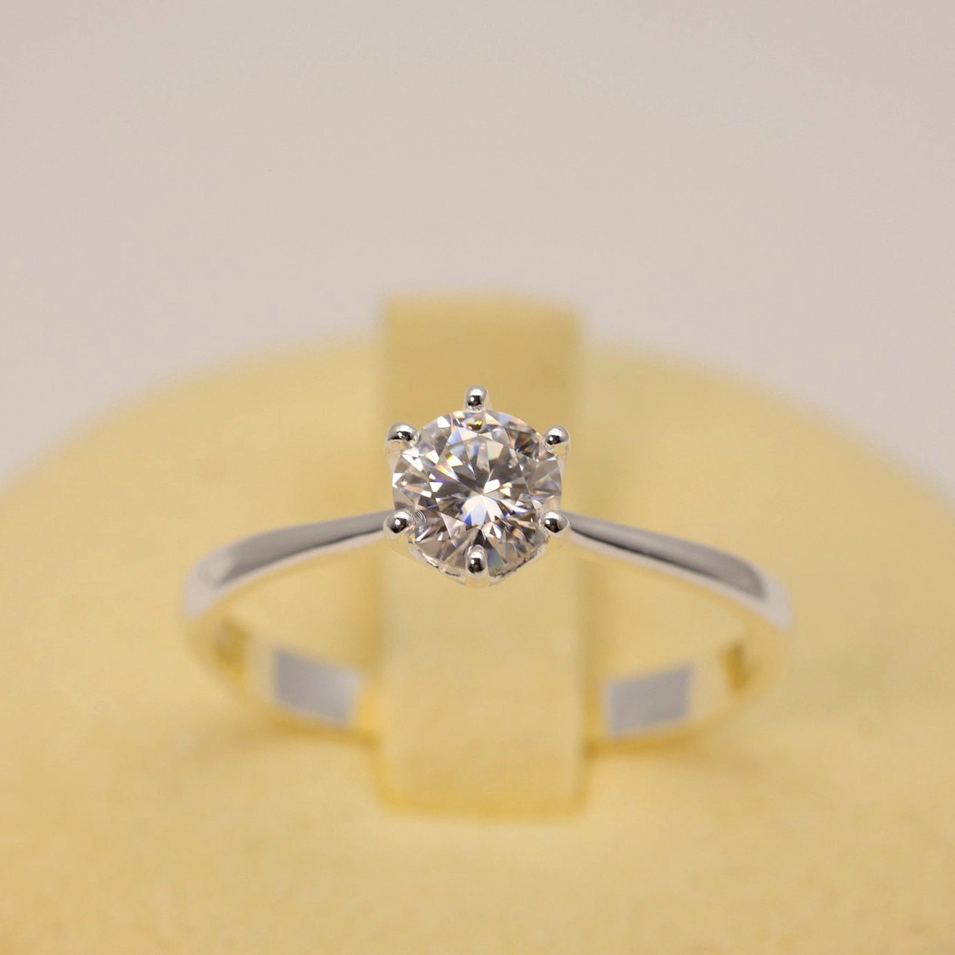Diamond ring on a yellow cushion with a plain background