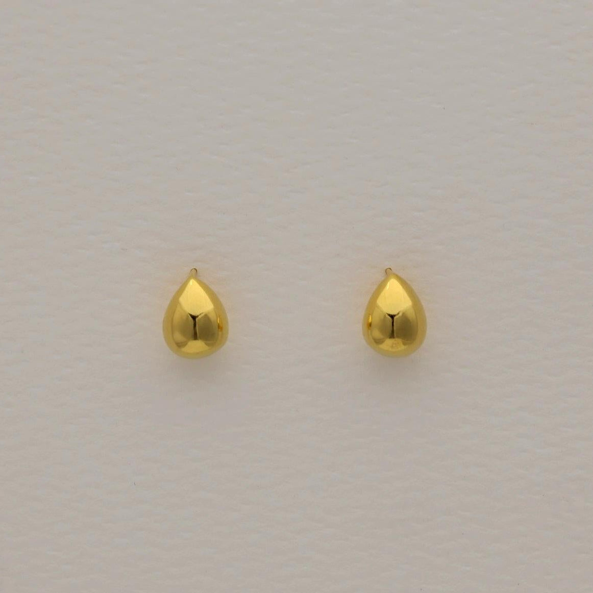 Front-facing Elva teardrop earrings in polished gold vermeil on a soft neutral background