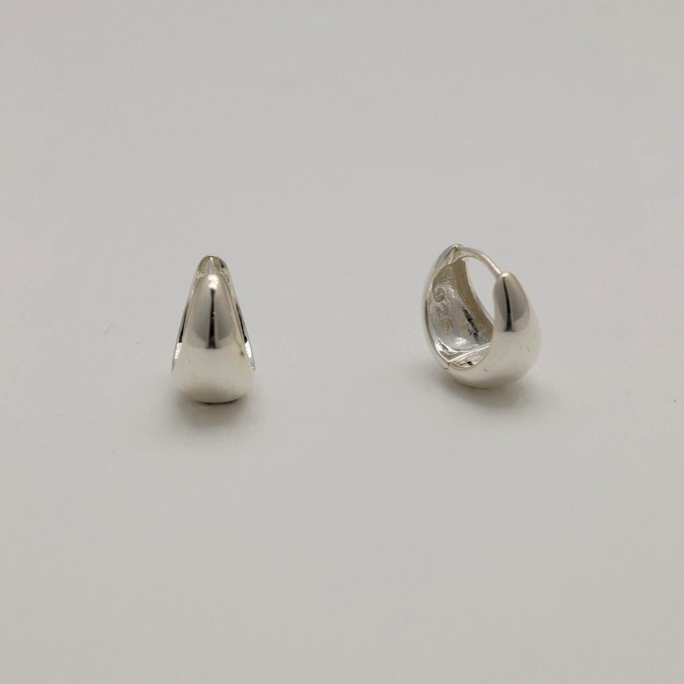 Two silver hoop earrings on a light gray background