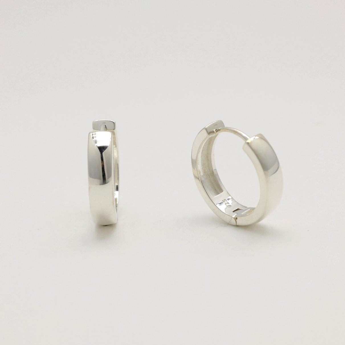 Two silver hoop earrings on a light gray background