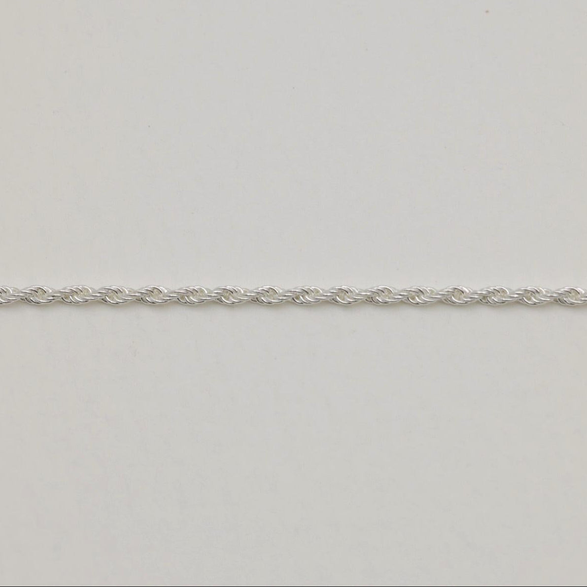 A sterling silver rope chain necklace with fine twisted links, displayed on a light neutral background. 42cm length, polished finish