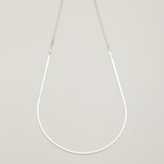 Flat lay of the Delia Chain Necklace in 925 sterling silver, showcasing its fine circular links.