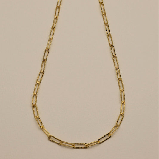 Josette Necklace full view – hammered gold rectangular chain on light background