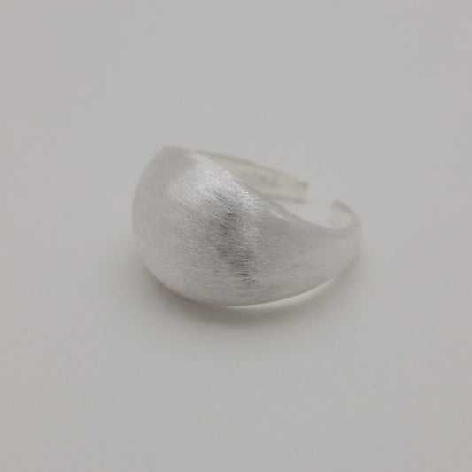 Angled lifestyle shot of brushed silver dome ring on neutral background