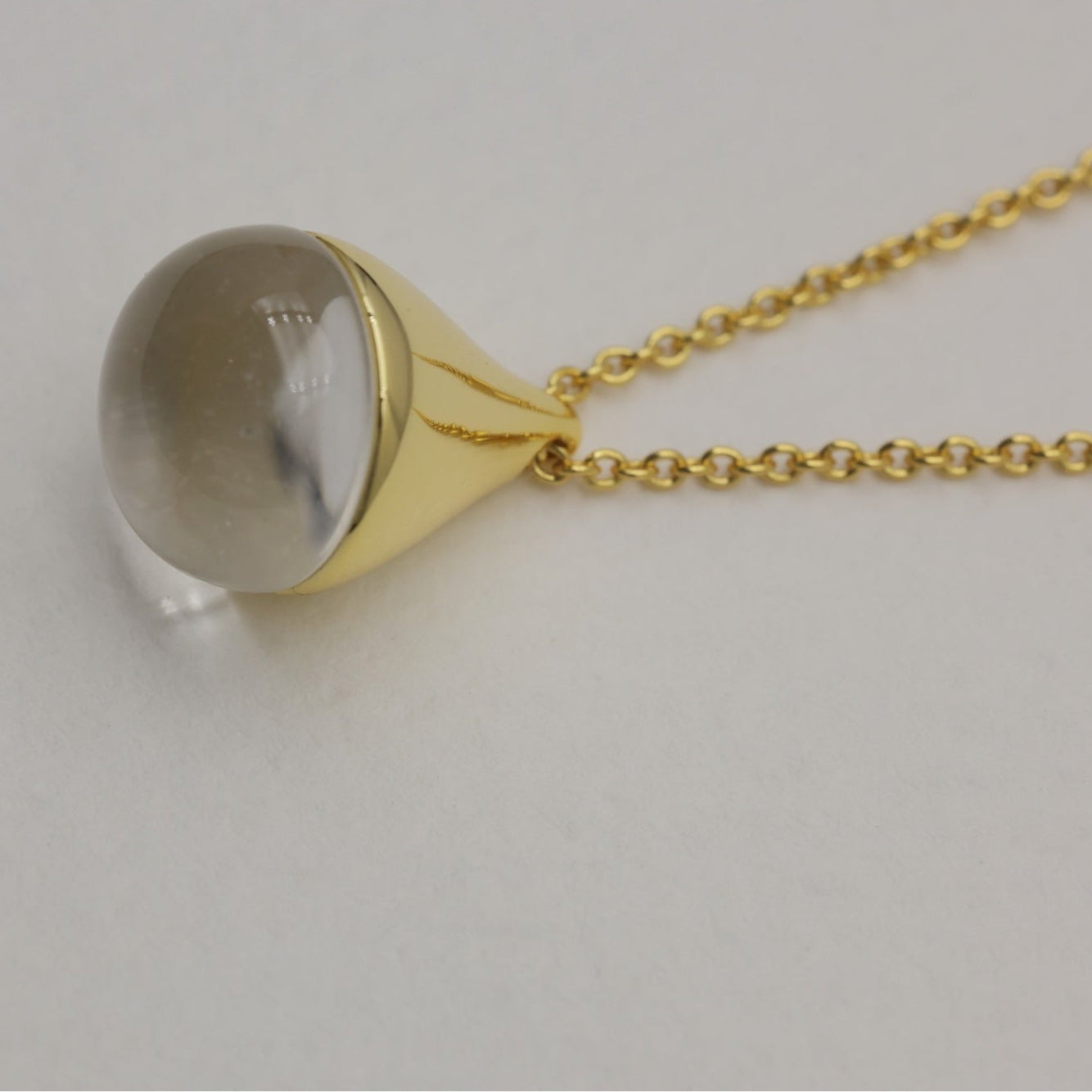 Close-up of teardrop pendant with clear crystal set in polished gold vermeil