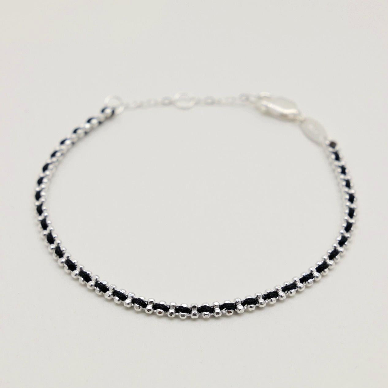 Angled view of the Agnès bracelet showing its curved shape and textured woven silver design.