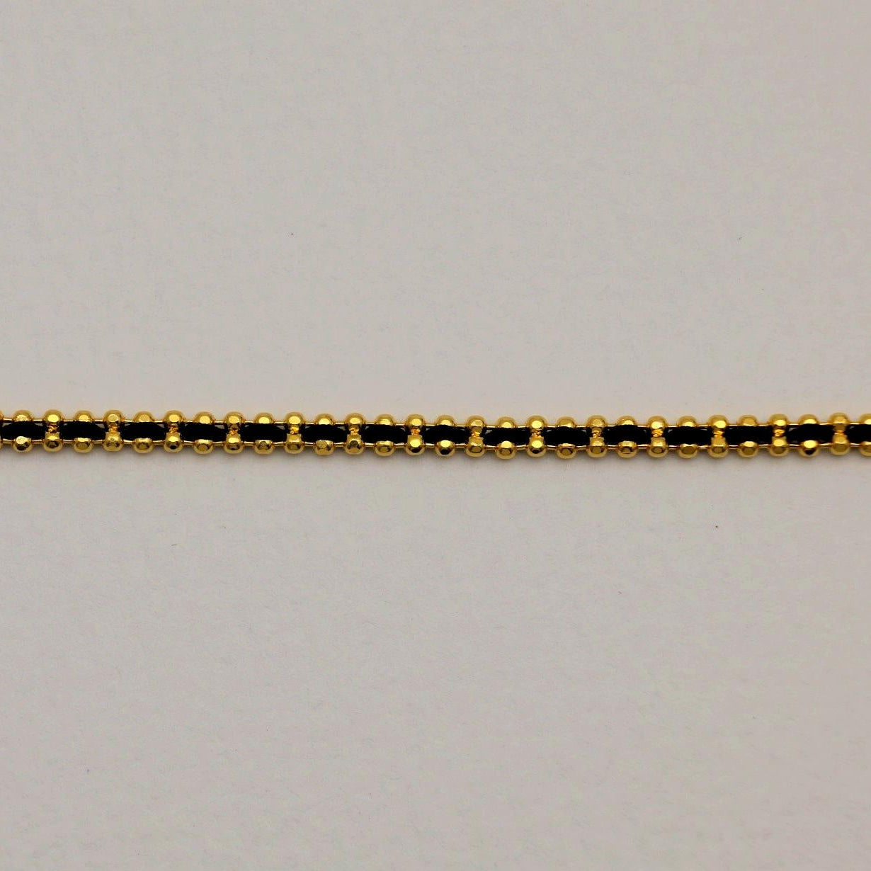 Close-up of the Agnès Woven Bracelet showing gold vermeil beading and black threading.