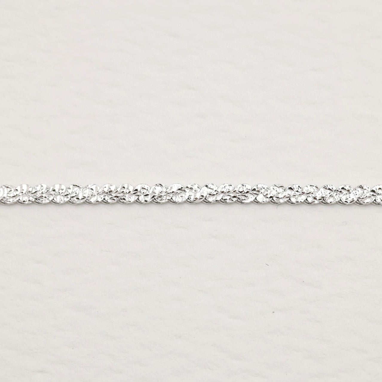 Close-up showing fluid silver discs linked seamlessly.