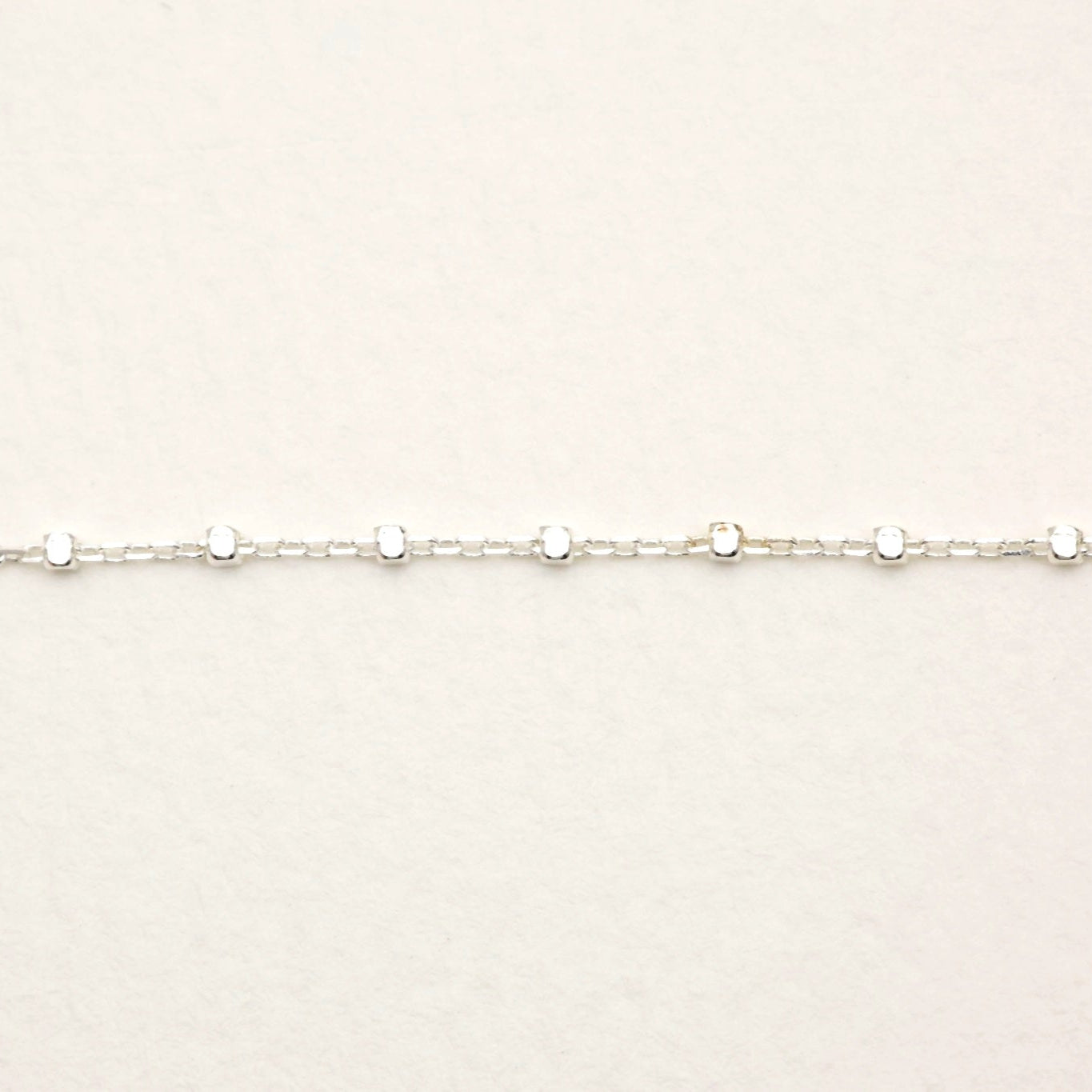 Close-up of the bracelet's circular disc details and fine box-style chain.