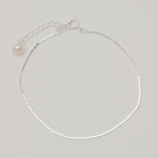 Sterling silver bracelet with extender and freshwater pearl charm, laid flat

