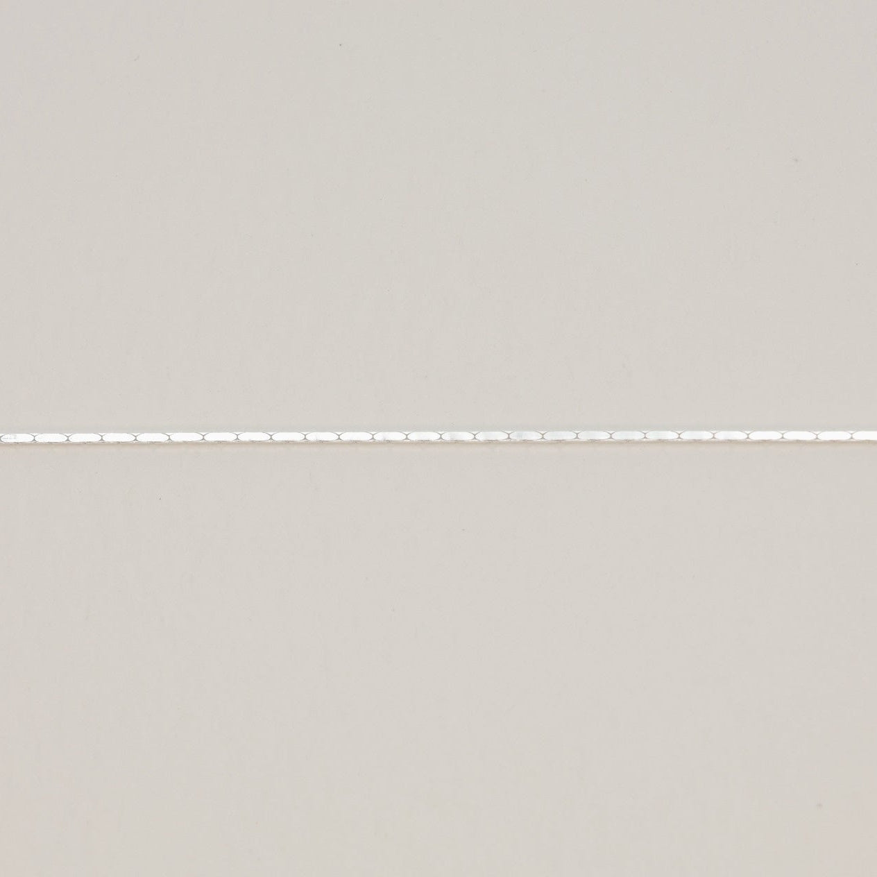 “Close-up of reflective silver bracelet chain and spring clasp”

