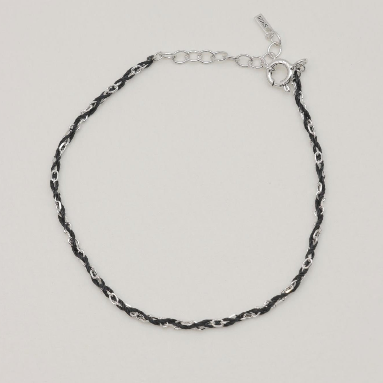 Sabine rope chain bracelet in sterling silver and black cord, full loop on soft background

