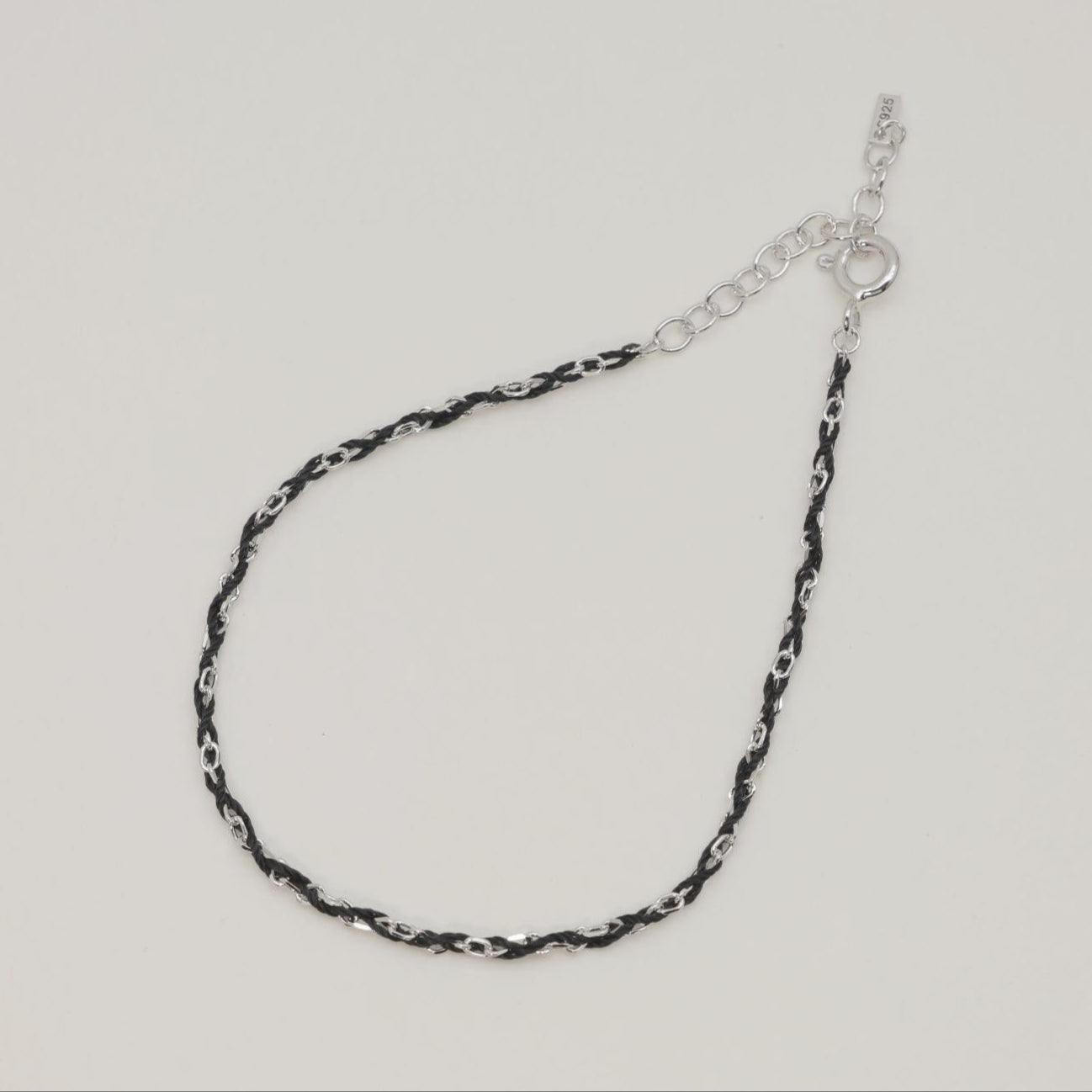Flattened detail shot of intertwined rope chain with silver and black texture