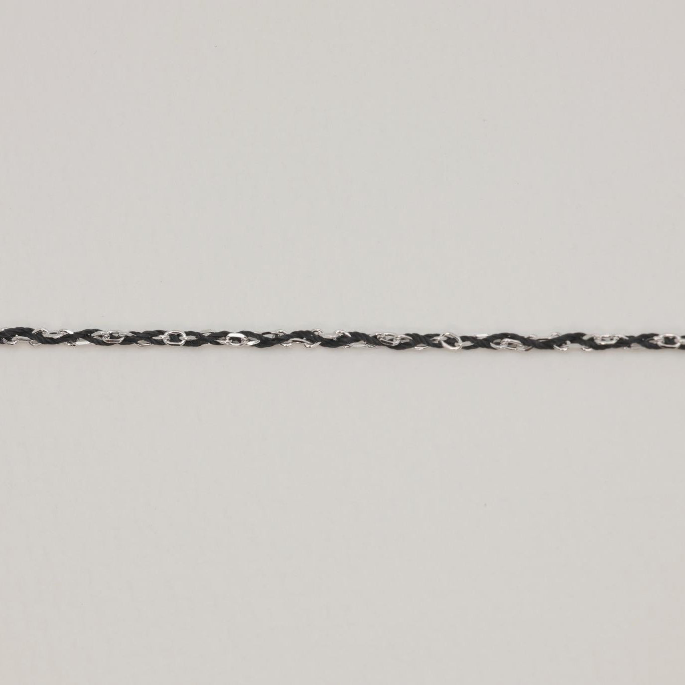 Close-up of silver and black cord braided bracelet with extension chain

